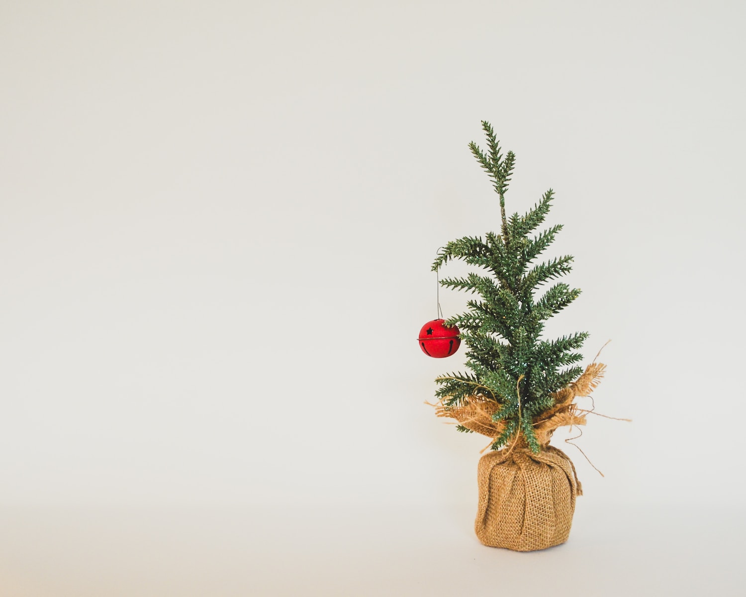 a small christmas tree with a red ornament on top of it