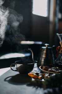 a steaming kettle and a plate of food on a table
