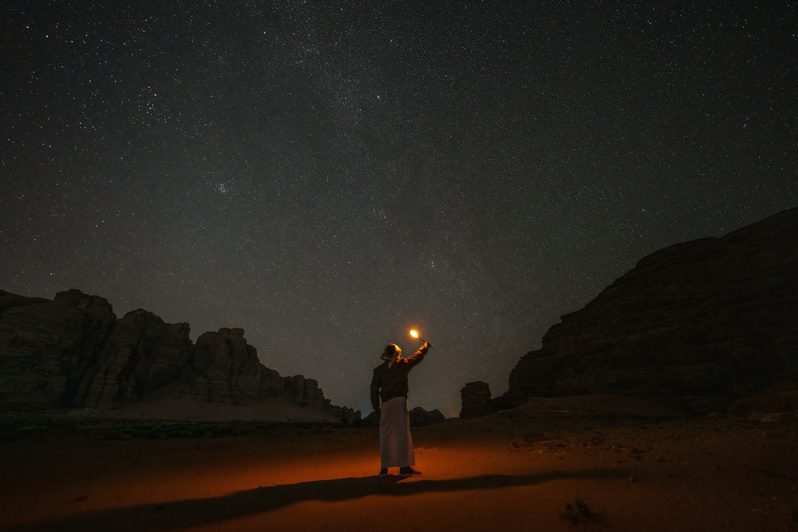 a person standing in the desert holding a lantern
