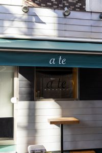 a restaurant with a green awning and a wooden table